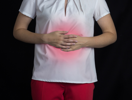 The girl holds on to the stomach on a black background, stomach pain, gastritis and ulcer, Helicobacterの写真素材