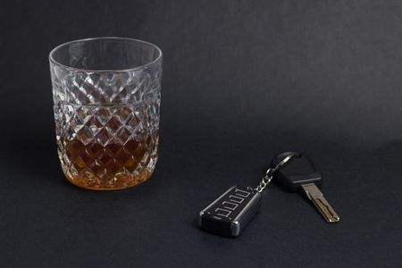 Car keys and glass with alcohol whiskey on black background, close-up, drunkの写真素材