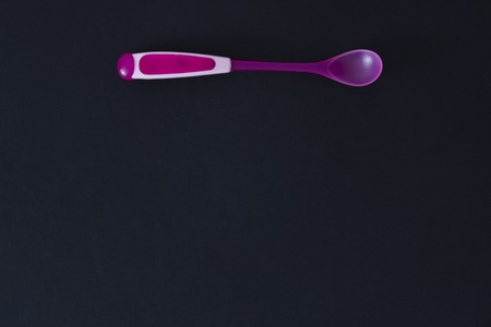 pink baby spoon on a black background and smallの写真素材