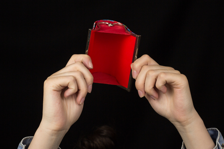 Female hands holding a red empty purse on a black background, close-upの写真素材