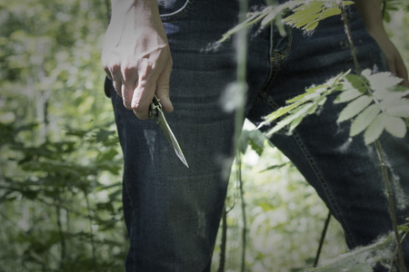 Man holding a knife in his hand in nature, close-up, killer, natureの写真素材