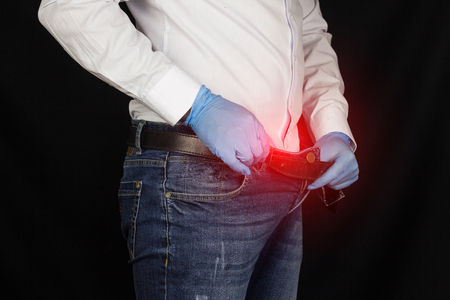 A man in medical gloves looks into his pants, close-up, prostatitis, medical glovesの写真素材