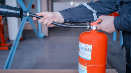 Instructor teaches the use of a fire extinguisher, discharge hose, class A and B, medium shotの写真素材
