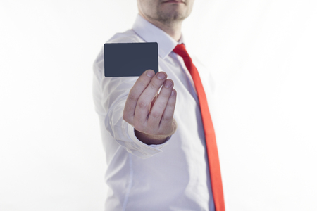 A man in a white shirt and red tie is holding a clean credit card for the inscription, white backgroundの写真素材