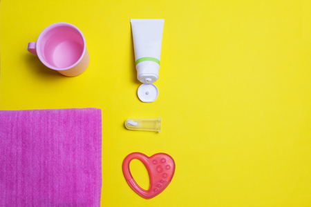 Brush for cleaning teeth and pasta, children's toy, towel and cup on a yellow background, toothpasteの写真素材