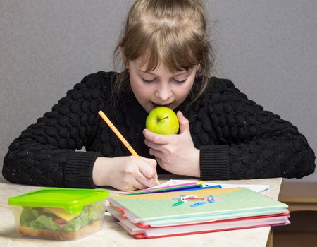 girl doing homework and eating apple, lunchの写真素材