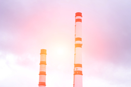 Two factory pipes against the sky, the sun, industryの写真素材