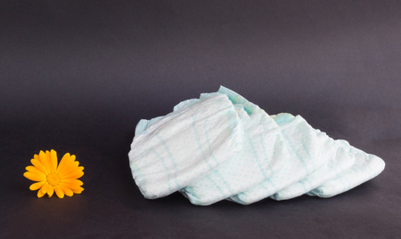 Baby diapers on a black background and an orange flower, flower and diapers, bodyの写真素材