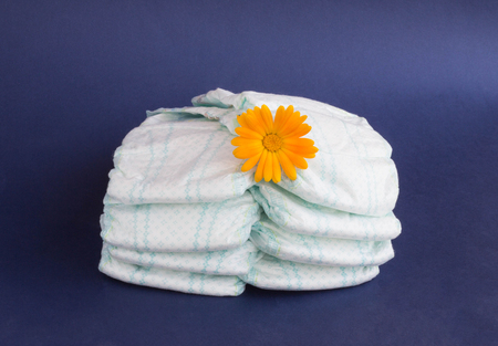Baby diapers on a blue background and an orange flower on diapers, hygieneの写真素材