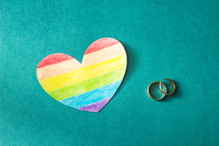 Wedding rings on a red background and a heart in the form of a flag lgbt, same-sex marriage, homosexualityの写真素材