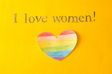 Heart in the form of a LGBT flag on a yellow background and the inscription I love women, the concept of lgbt, lesbianの写真素材