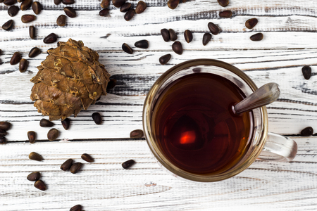 Cedar cone and pine nuts, a cup of tea on a white wooden background, close-upの写真素材