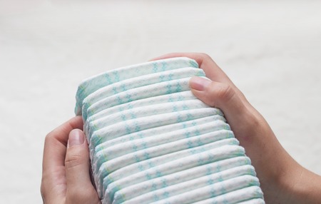 Mother keeps the package with baby diapers, close-up, women's hands and diapersの写真素材