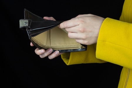Girl holding an empty purse in hands, close-up, black background