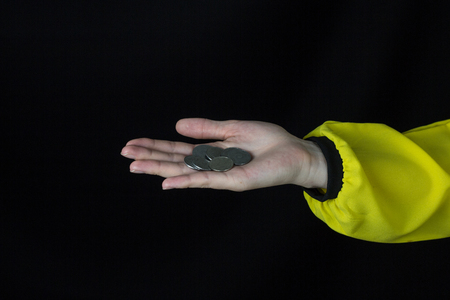 Girl holding a coin on his outstretched hand, in the palm of his hand, close-up, black background, studio, hand and coinの写真素材