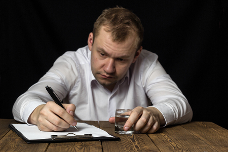 Sad man businessman drunk signing contract, male alcoholism, signing documents in a state of intoxication, handsomeの写真素材