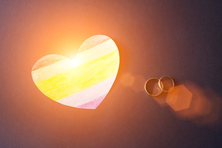 Wedding rings on a blue background and a heart in the form of a flag lgbt, same-sex marriage and sun, beamsの写真素材