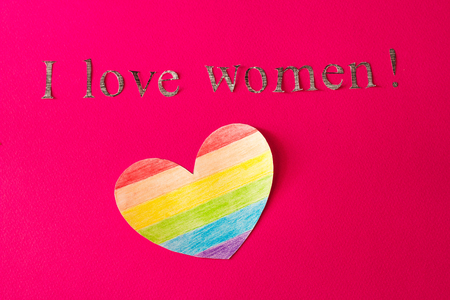 Heart in the form of a LGBT flag on a red background and the inscription I love women, the concept of LGBTの写真素材