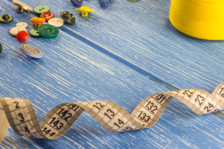 Threads of buttons and centimeter tape on a blue wooden background, dressmakingの写真素材