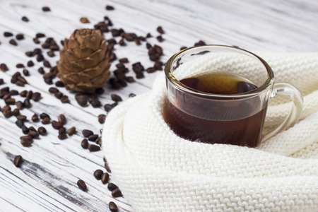 A cup of tea and pine nuts with a cone on a white wooden background, close-up, teaの写真素材