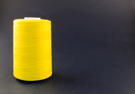 Yellow thread reel on a blue background, close-up