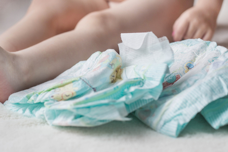 Baby diapers and a small child sitting next to himの写真素材
