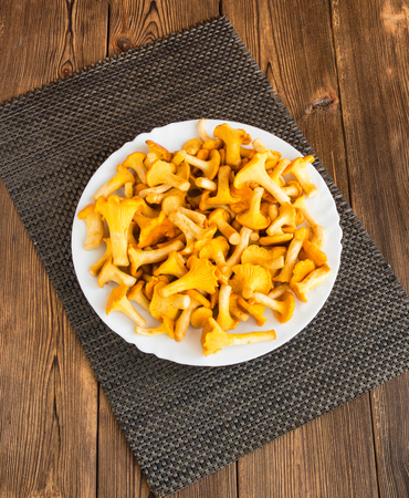 Plate with mushrooms chanterelles on a wooden background, darnerの写真素材