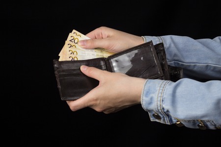 woman holding a wallet with money, close-up, Black backgroundの写真素材