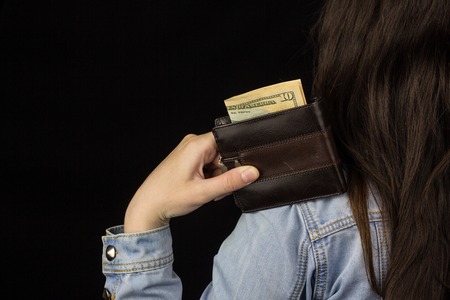 woman holding a wallet with money, close-up, Black background, dollarsの写真素材