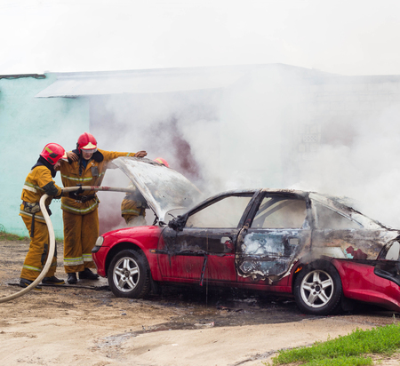 BOBRUISK, BELARUS - JULY 25, 2018: Two firemen extinguish a burning car, fire, smokeのeditorial素材