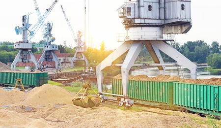 The port crane makes loading of wood chips into the freight cars of the train, industrial,...