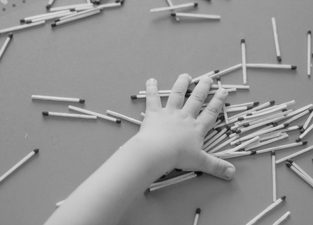 A small child plays with matches, takes matches from the table, close-up, black and white, fire, matchesの写真素材