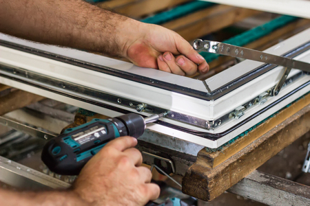 Production of pvc windows, a man screws a screwdriver into a pvc window, close-up, arm screwdriver,...