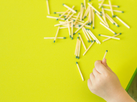 A small child plays with matches, a child's hand takes matches from the table, a close-up, a fire,...
