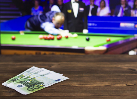 Euro money on the background of a TV on which show a game of snooker, sports betting, billiards