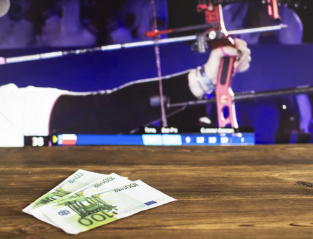 Euro money on the background of a TV on which show sports archery, sports betting, archery