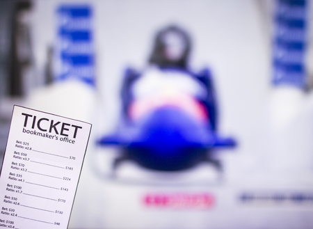 Bookmaker ticket on the background of the TV on which show toboggans, bobsled, sports betting,...