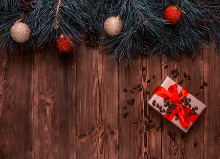 A box with a Christmas gift and pine nuts on a brown wooden background, pine paws and Christmas balls, a New Year gift, celebration, copy spaceの写真素材