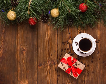 A cup of coffee and a gift for the New Year and Christmas holiday, on a wooden background with spruce branches and New Year toys, decorationの写真素材