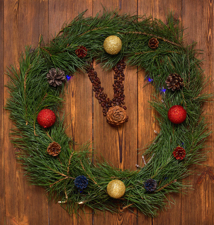 New Year's watches made of fir branches, cones and pine nuts, decorated with new balls, on a wooden background, show the time at five to twelve, clock, holidayの写真素材