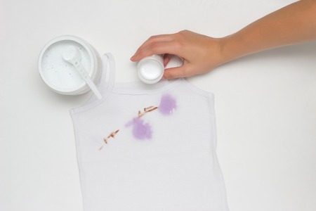 Girl puts on a dirty white T-shirt with stains, removes stains, hands, close-up, white background, bleachの写真素材