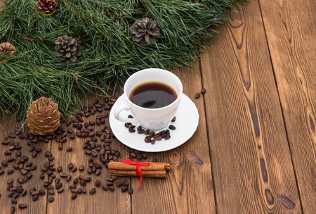 A cup of coffee with cinnamon and fir branches on a wooden background, New Year's holidays, a place for an inscription, celebrationの写真素材