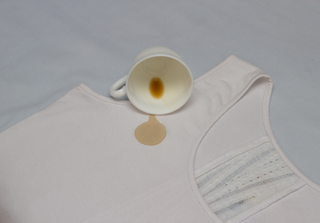 Spilled coffee cup on white shirt, coffee stain on clothes, close-up, cup, whitenerの写真素材