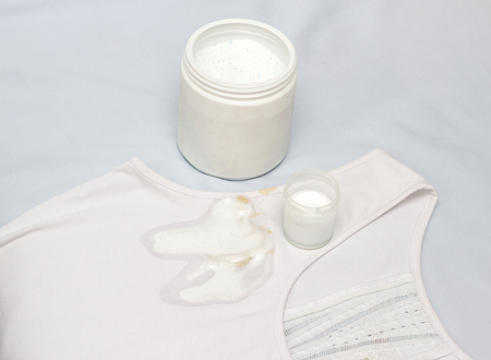 Spot on a white T-shirt filled with stain remover, fighting stains on clothes, white T-shirt, close-up, container with stain remover, bleachの写真素材