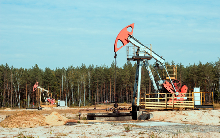 Oil well for the production of oil and gasoline and gas on the background of the forest, the production of gasoline, pumpjack, extraction of petroleumの写真素材