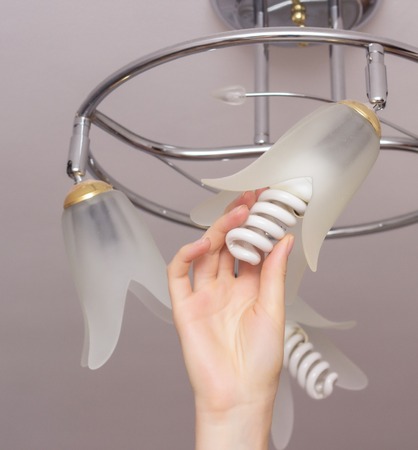 Installing an energy-saving modern spiral bulb in a chandelier suspended from the ceiling, close-up, arm, saving, economicalの写真素材