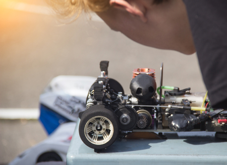 The participant checks and adjusts the radio-controlled car before the start of the competition, close-up, self-made sports competitions, repairの写真素材