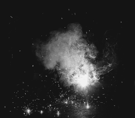 Welder at the factory in a welding mask welds metal parts, welding and sparks, black and whiteの写真素材