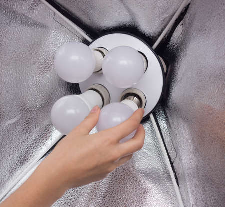Installing a diode energy saving light bulb in a soft box for lighting, hand, close-up, professionalの写真素材