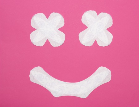 Smiling face made of female pads on a pink background, protection, discharge, close-upの写真素材